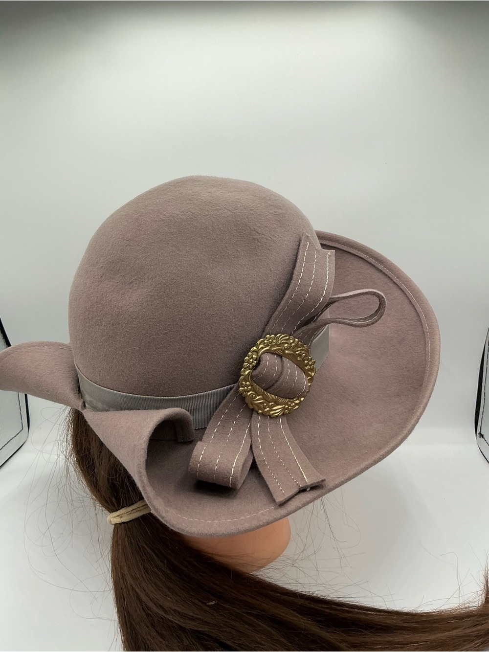 Wool hat with an asymmetrical brim, ribbon accent, and gold-toned buckle